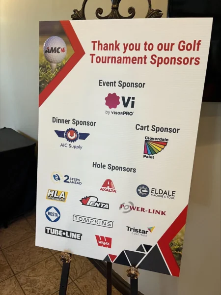 A sign propped up by AMX thanking their Golf Tournament Sponsors, with the Event Sponsor listed as Vi by visorPRO