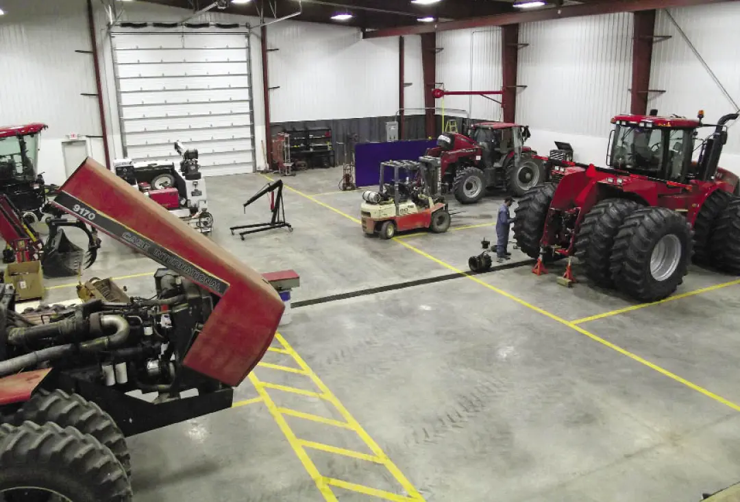 An interior shot of a Torgerson's Dealership, four red farm machinery are lined on either side of the wall.